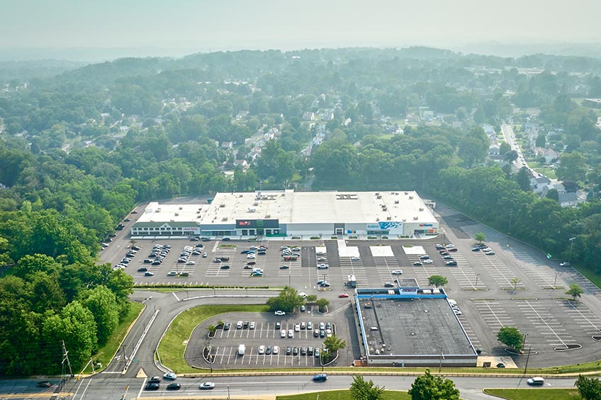 Overhead shot of Broomall Commons shopping center and its adjacent parking lot, captured from a high vantage point.