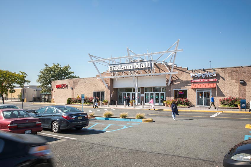 Storefront at Hudson Mall shopping center with various parking spaces.