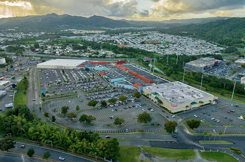 Aerial view of Shops at Caguas shopping center and its adjacent parking lot, captured from a high vantage point.
