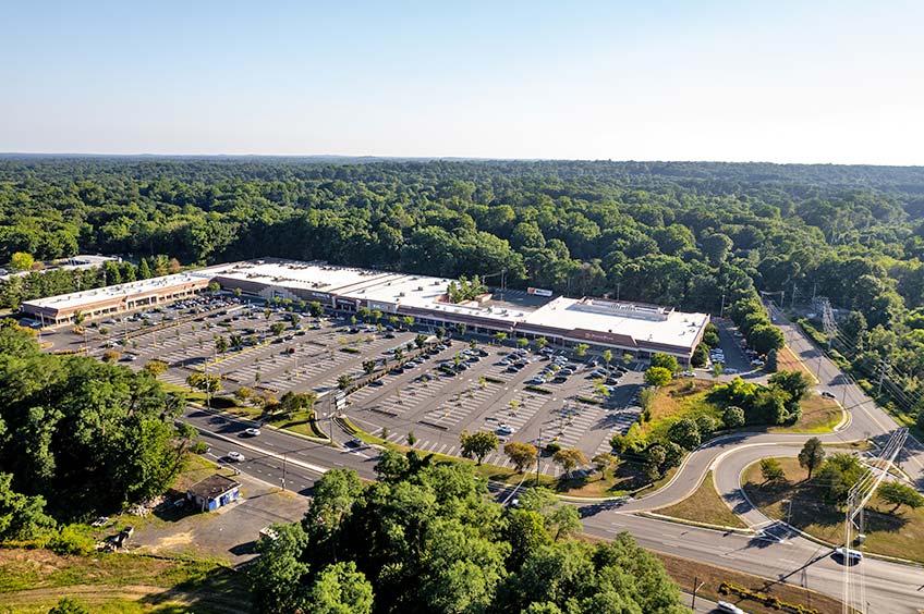 Aerial view of Town Brook Commons shopping center and its adjacent parking lot, captured from a high vantage point.